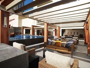 Un área de piscina exterior con mobiliario de descanso y una pérgola.
