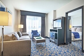 Habitación de hotel con sofá, una mesita, televisión y cama.