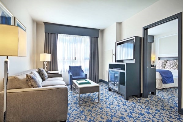 A hotel room with a sofa, a small table, a TV, and a bed. - San Francisco | City Stay | Fitness Center & Game Room | 3BR Sleeps 6 (San Francisco)