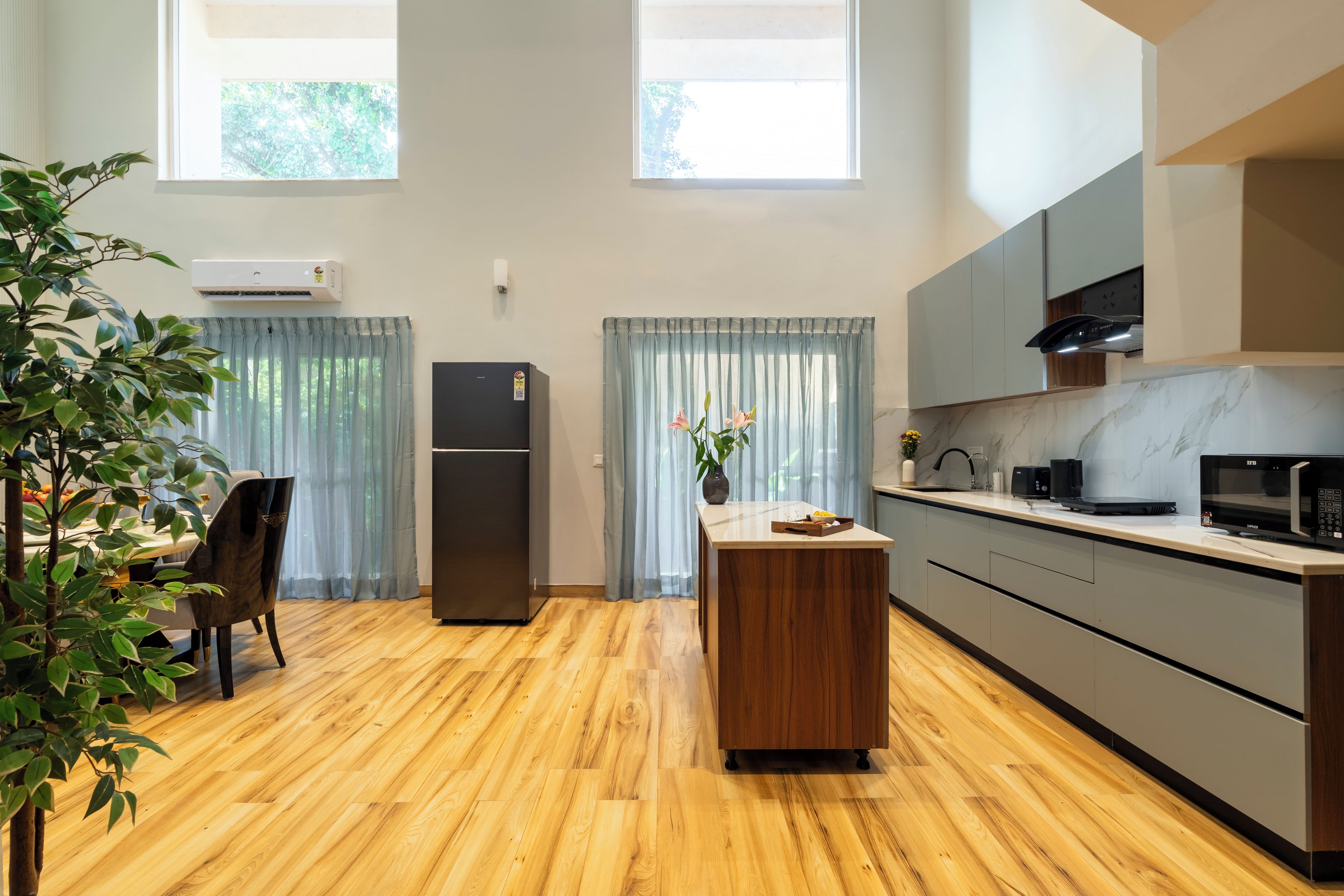 Una cocina moderna con suelo de madera, refrigerador empotrado, microondas y lavaplatos.