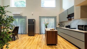 Una cocina moderna con suelo de madera, refrigerador empotrado, microondas y lavaplatos.