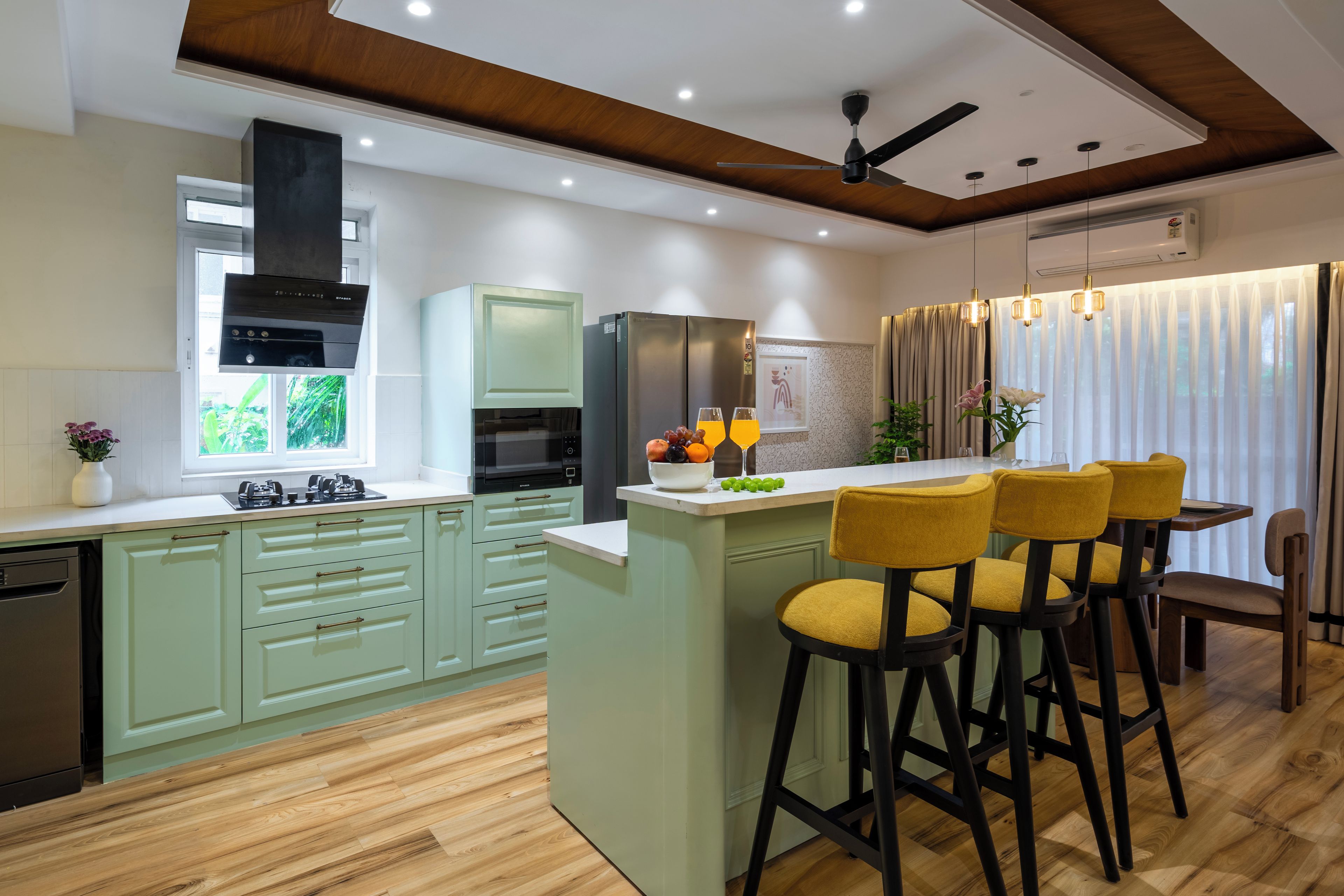 A modern kitchen with a central island, bar stools, and a dining area with a table and chairs.