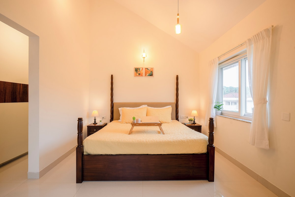 Quarto com cama de madeira, mesas de cabeceira, luminária de cabeceira, janela com cortinas e luminária fixada na parede.