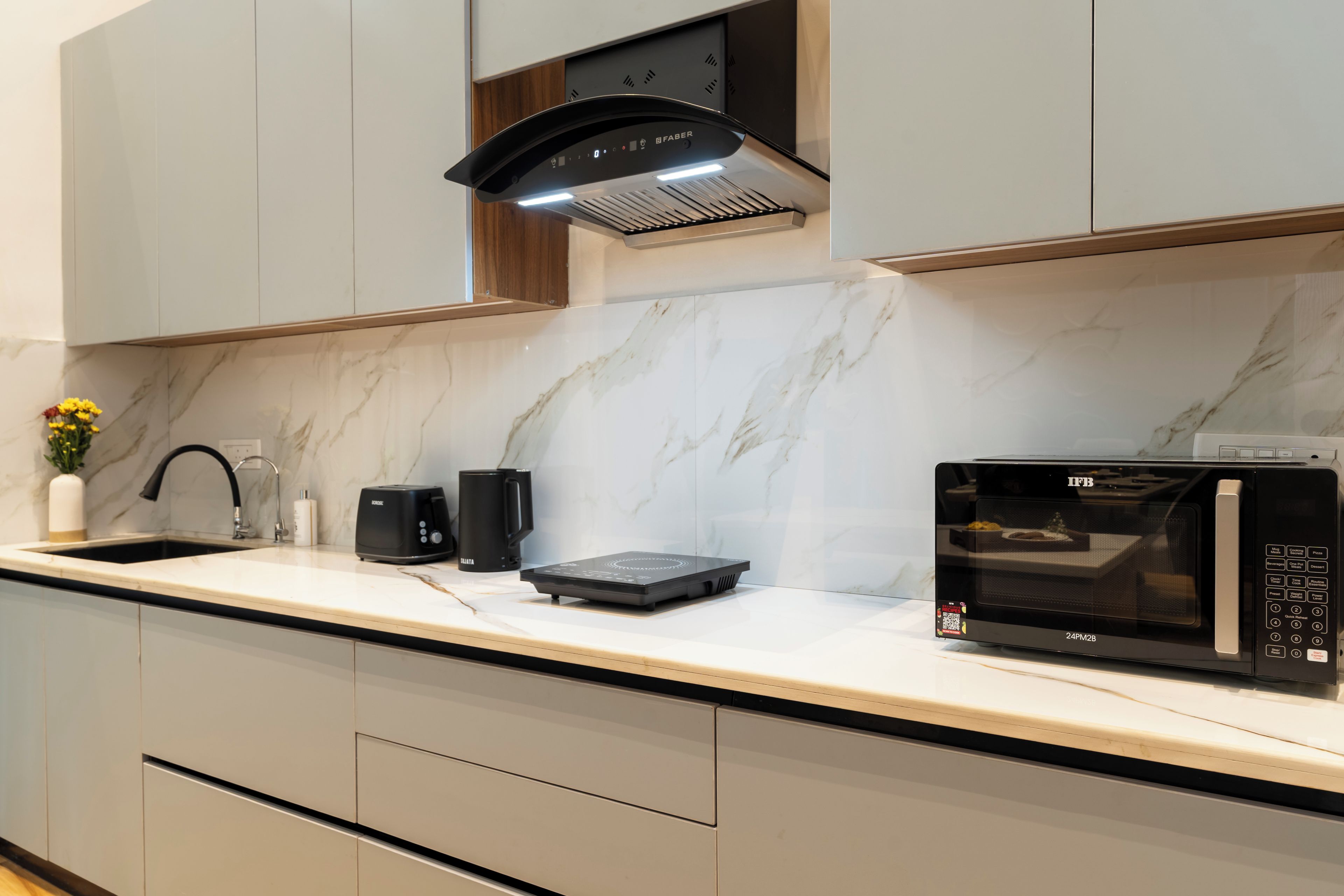 A modern kitchen with a built-in microwave, a toaster, and a coffee maker on the countertop.