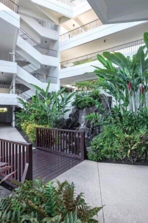 Een meerlaagse atrium met een centrale rotstuin, houten terras en moderne architectuur.
