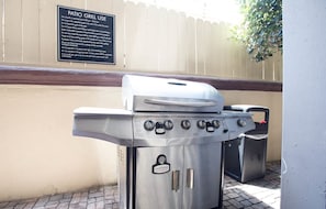 A patio grill with a sign above it, a metal grill, and a trash can nearby. - Anaheim | Couples Magic Getaway | Pool + Hot Tub (Anaheim)