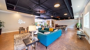 A spacious living area with a blue sofa, a coffee table, and a lamp. There is a dining area with chairs and a table in the background. - Anaheim | Couples Magic Getaway | Pool + Hot Tub (Anaheim)