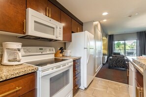 Una cucina moderna con microonde, fornelli e frigorifero. C'è una macchina da caffè sul bancone e un'area pranzo con vista sull'esterno.
