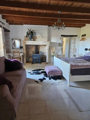Una habitación acogedora con chimenea, una cama, un sofá y un comedor.