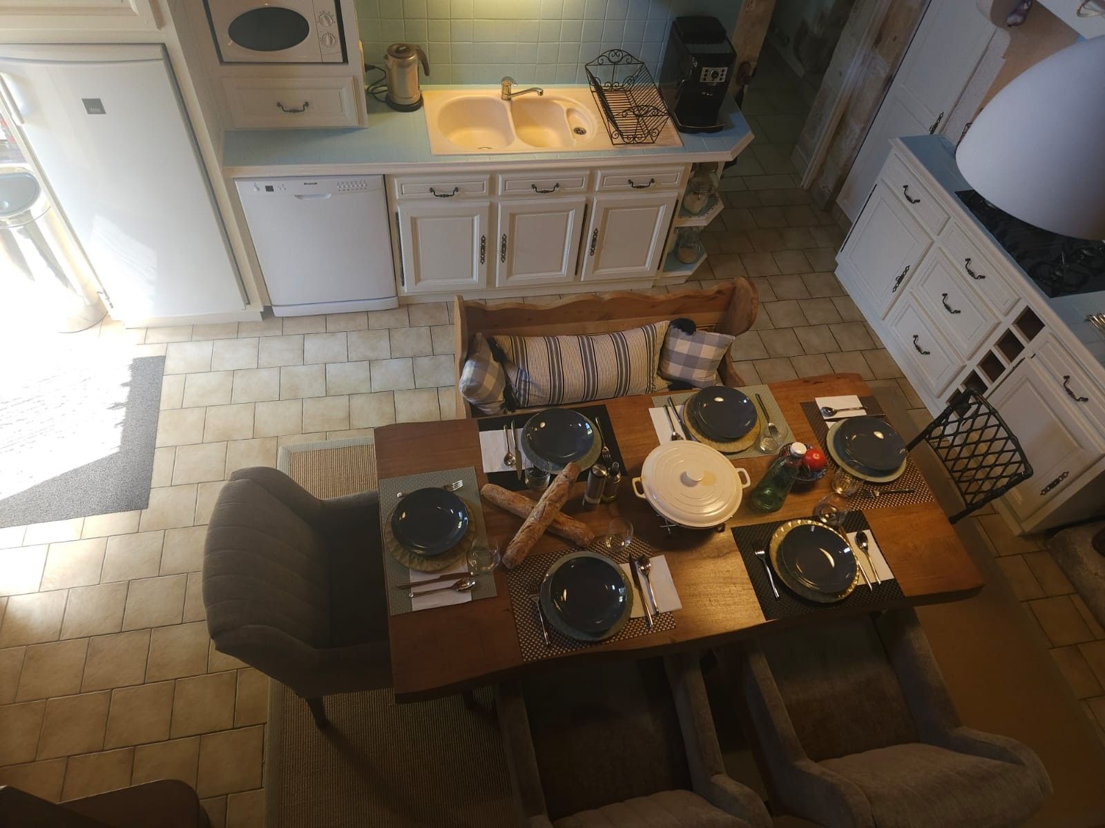 A dining area with a table set for four, a sofa, and a kitchen in the background.