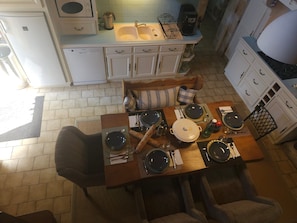 Un comedor con una mesa preparada para cuatro, un sofá y una cocina al fondo.