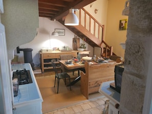 Una cocina con una mesa de madera, sillas, estufa y una lámpara colgante.