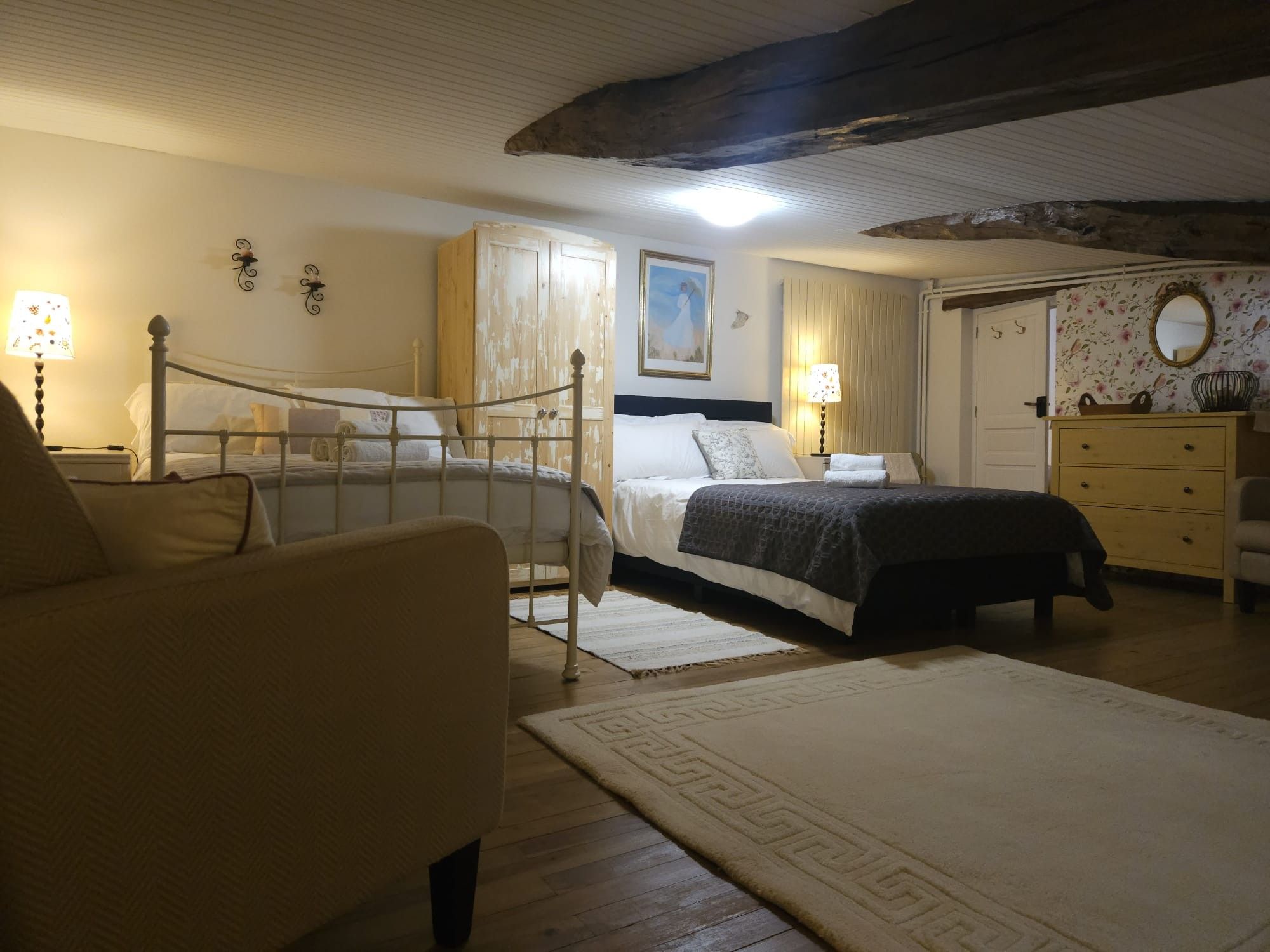 Een slaapkamer met twee bedden, een dressoir, een stoel en een schilderij aan de muur.