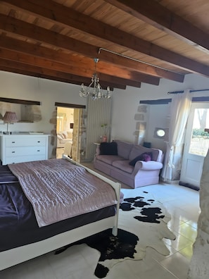 Un dormitorio con cama, sofá, candelabro y alfombra de cuero de vaca.