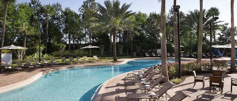 A swimming pool with lounge chairs and umbrellas, surrounded by palm trees.