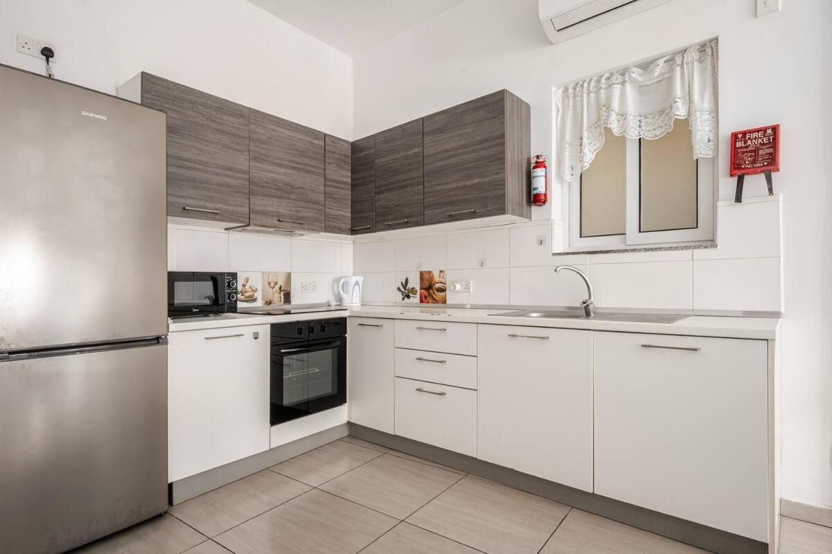 A modern kitchen with a stainless steel refrigerator, a microwave, a stove, and white cabinets.