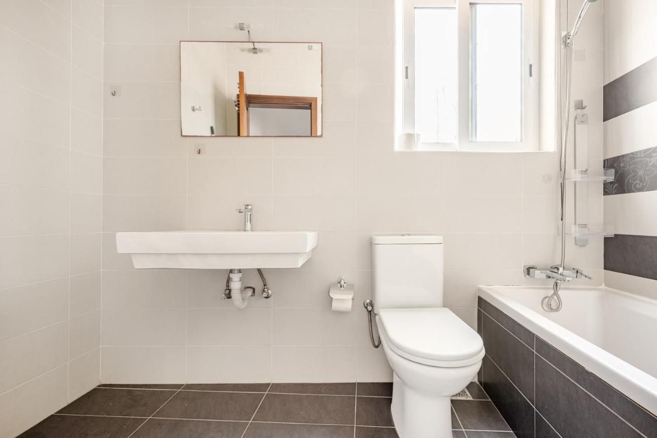 Un baño con lavamanos, inodoro y bañera blancos.