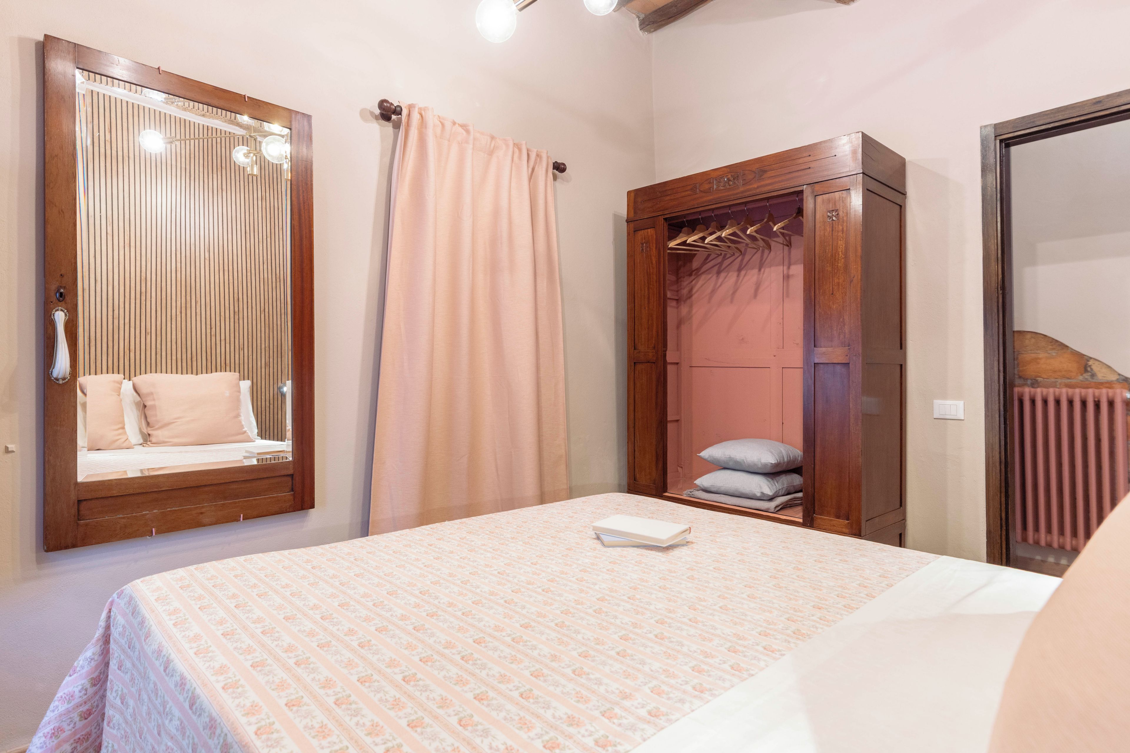 A bedroom with a bed, a wardrobe, a mirror, and a radiator.