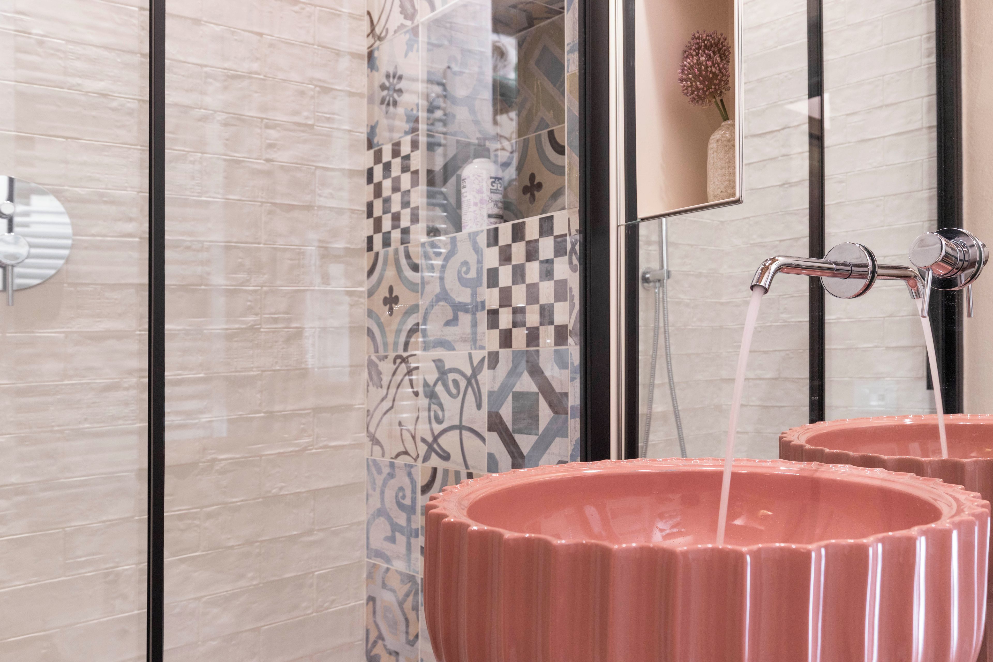 A bathroom with a shower, a mirror, and two pink sinks.