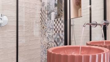 A bathroom with a shower, a mirror, and two pink sinks.