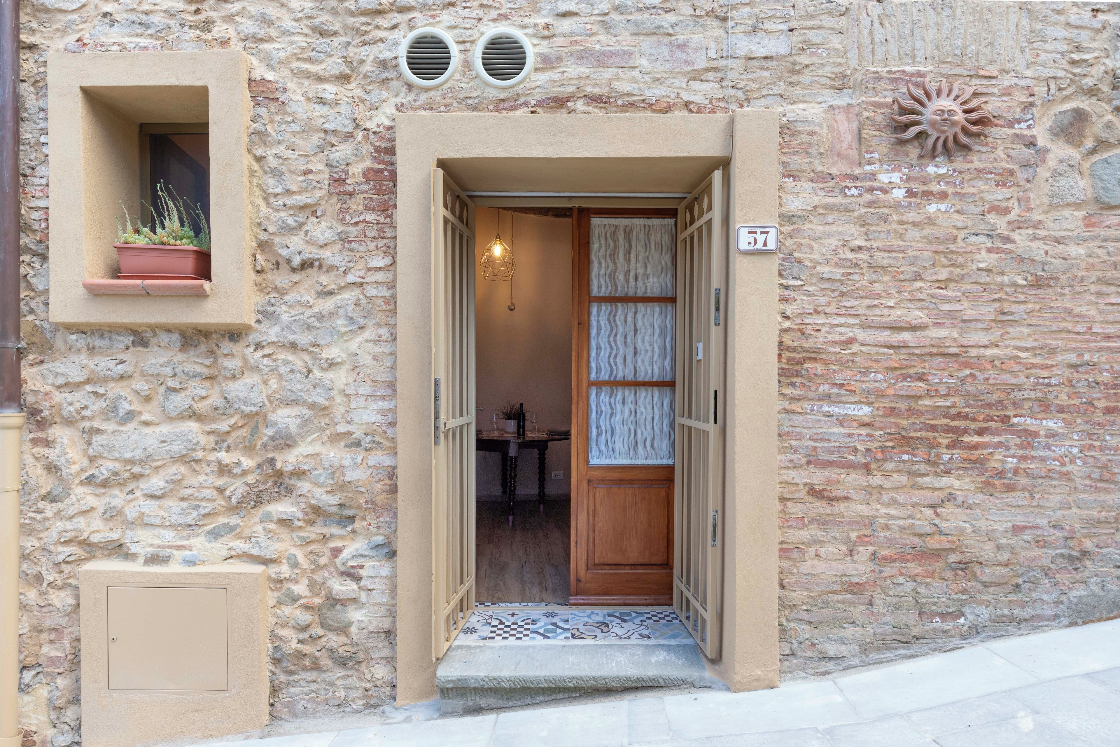 A stone building with a wooden door, a potted plant, and a number '57' sign.
