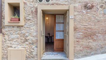 A stone building with a wooden door, a potted plant, and a number '57' sign.