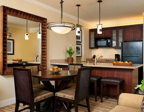 Una cocina moderna con armarios de madera oscura, una isla central y un comedor con mesa redonda y sillas.