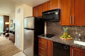 Una cocina con armarios de madera, un refrigerador de acero inoxidable, un microondas y una encimera de granito.