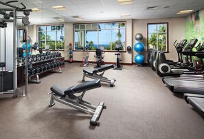 Uma academia com equipamentos de exercícios, janelas amplas e vista para o exterior.