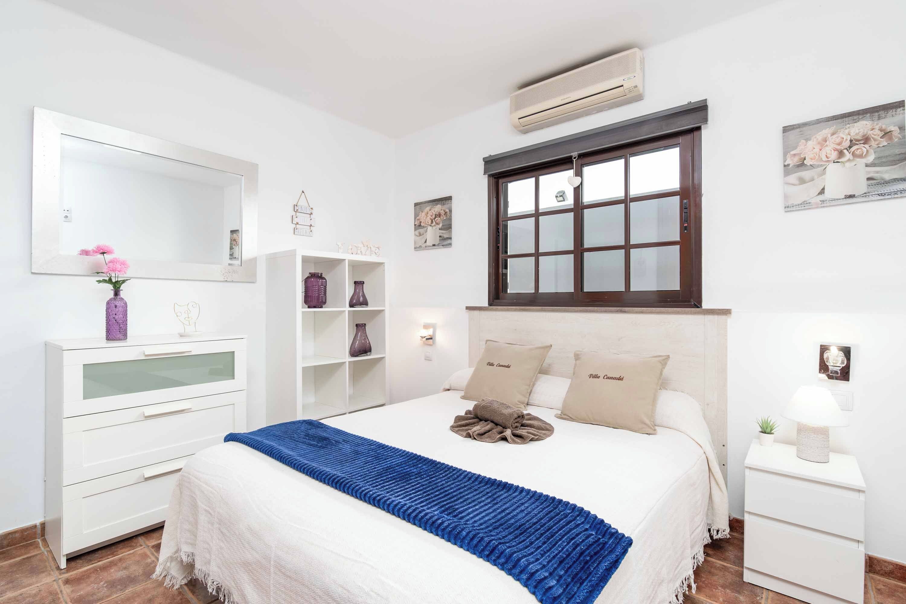 Un dormitorio con una cama grande, un aparador, un tocador y un ventanal con vistas.