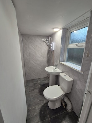 Un baño con inodoro, lavamanos y ducha.