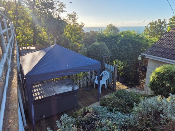 Un patio con una parrilla, mobiliario exterior y vistas al océano.
