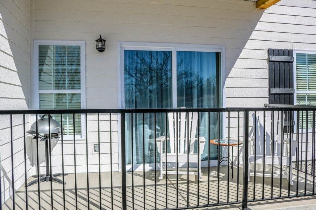 A covered outdoor area with a grill, chairs, and a table.
