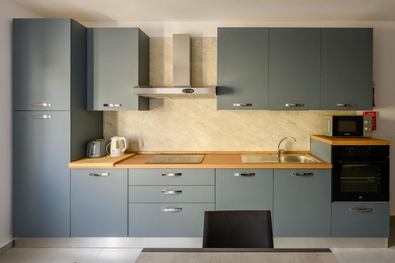 Una cocina moderna con armarios grises, una campana extractora de acero inoxidable, un microondas y un horno empotrado.
