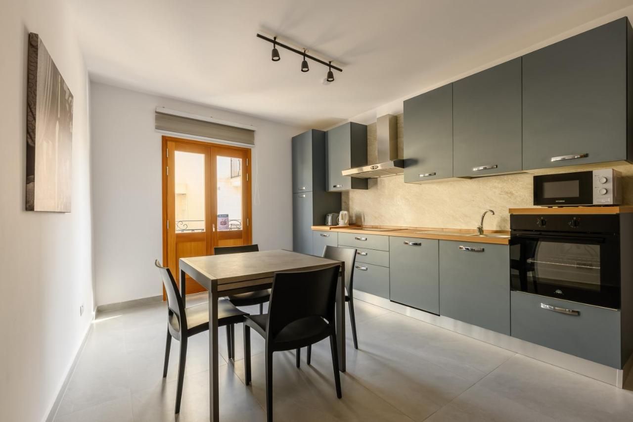 Una cocina moderna con armarios grises, encimera de madera y un comedor con mesa y sillas.