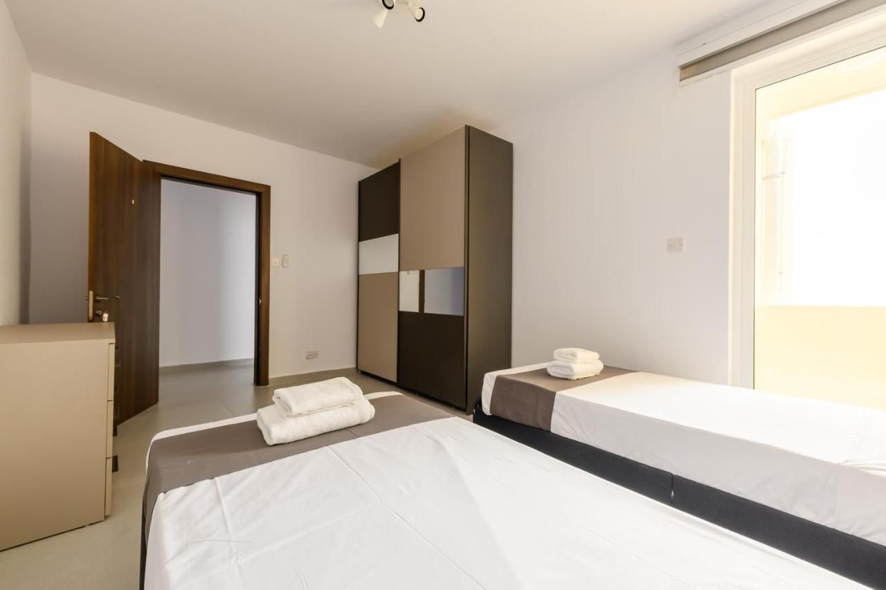 Une chambre d’hôtel avec deux lits, une armoire, un bureau et une porte de salle de bain.