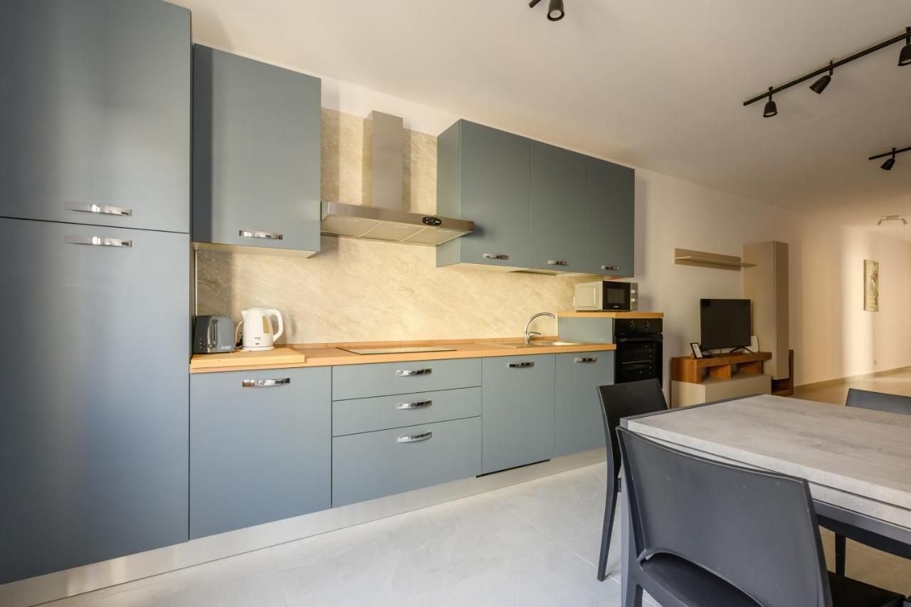 A modern kitchen with grey cabinets, a wooden countertop, and a dining area with a table and chairs.