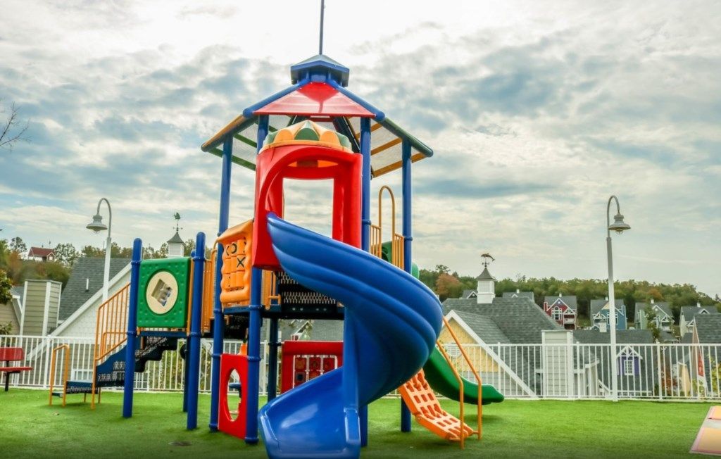 A playground with a blue slide, a red and yellow climbing structure, and a green play area.