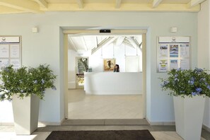 A reception area with a reception desk, a bulletin board, and potted plants. - Piccolo Hotel (Porto Ottiolu)