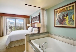 Ein Hotelzimmer mit einem großen Bett, einem Badezimmer mit Badewanne und Blick auf die Stadt durch das Fenster.