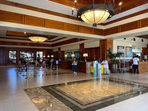 Un vestíbulo de hotel con una recepción, una lámpara de araña grande y un mostrador de registro.