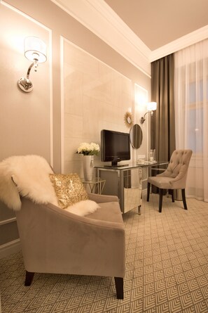 A hotel room with a plush armchair, a television, a small table with a vase of flowers, and a chair. - Hotel Jech (Hlavní město Praha)