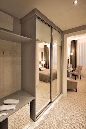 A hotel room with a mirrored wardrobe, a bed, a sitting area with a chair, and a small table. - Hotel Jech (Hlavní město Praha)