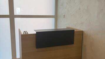 Un mostrador de recepción con acabado de madera y superficie negra, ubicado junto a un ventanal con paneles de vidrio esmerilado.