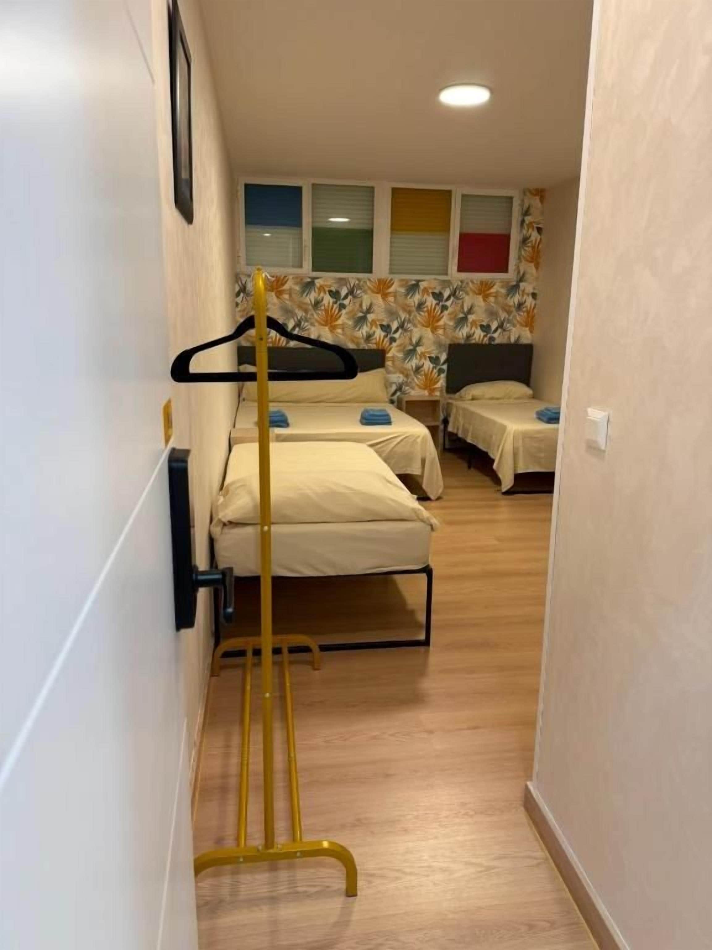 Un couloir étroit, avec un lit à droite et un lit à gauche, tous deux recouverts de draps blancs.