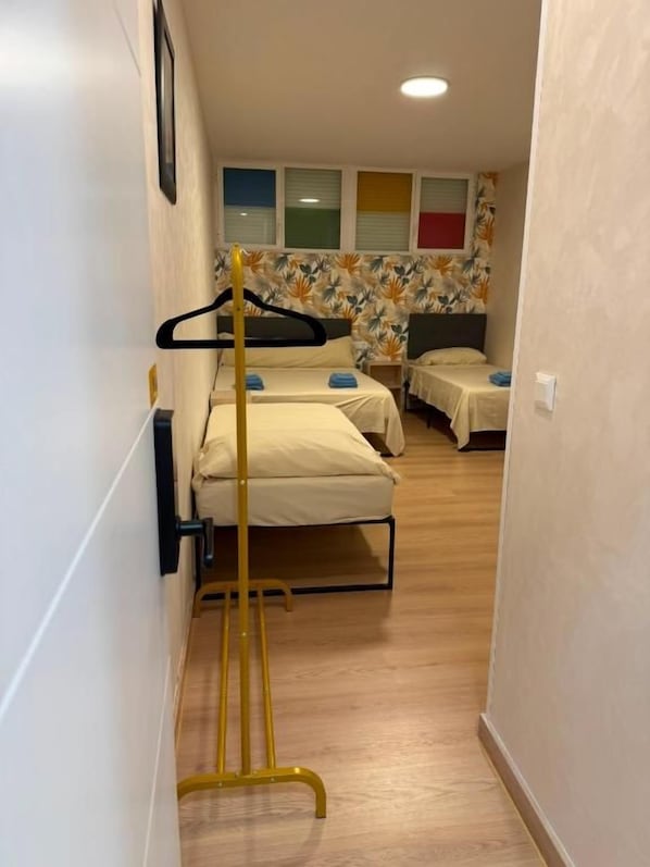 A narrow hallway with a bed on the right and a bed on the left, both with white bedding. - Multi Hostal BM 71 (Madrid)