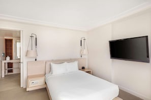 Una habitación de hotel con una cama, mesitas de noche, un televisor y un espejo.