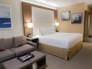 Una camera d'albergo con un letto, un divano, un comodino e una scrivania.