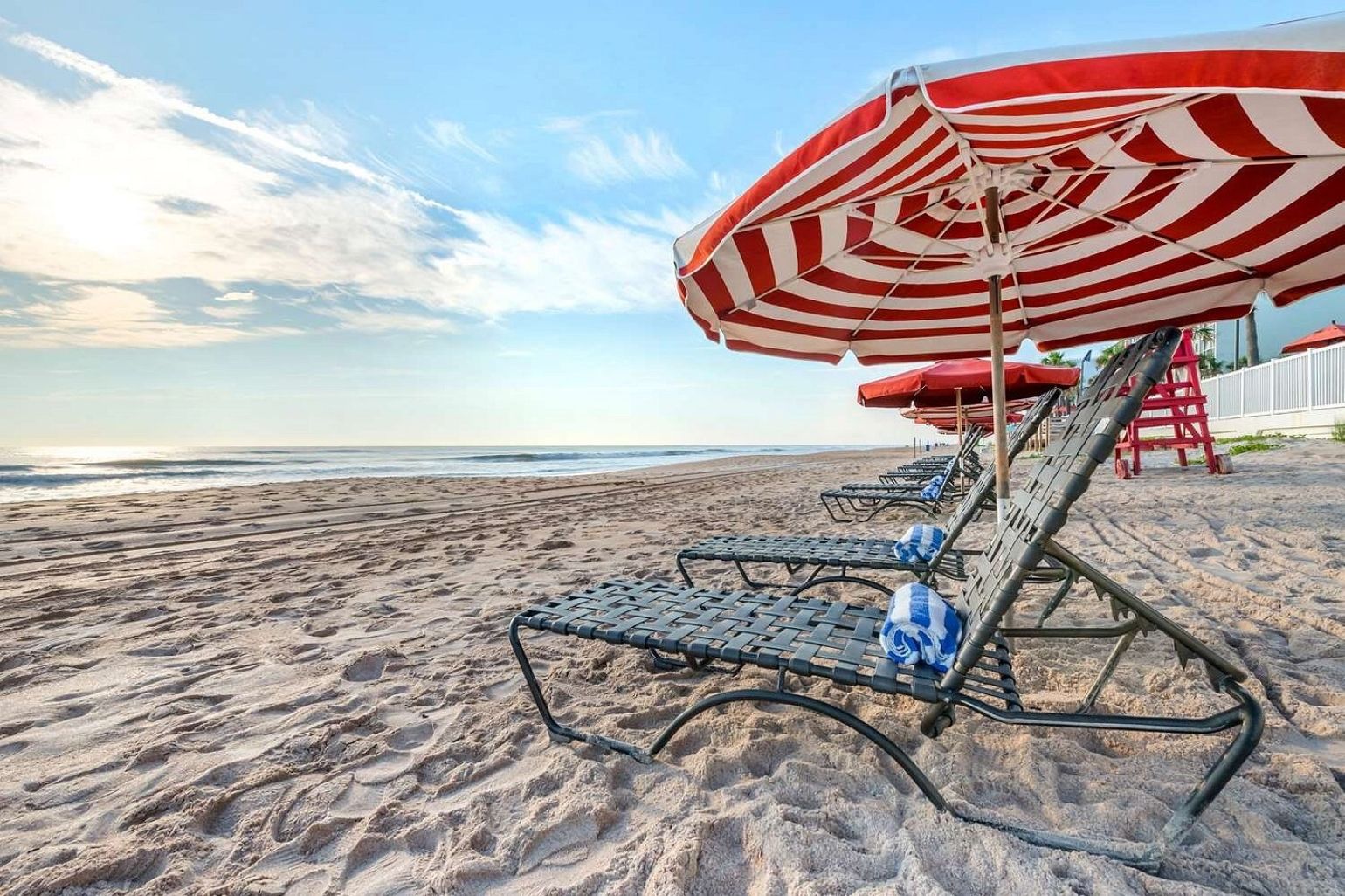 Una spiaggia con lettini e un ombrellone a righe.