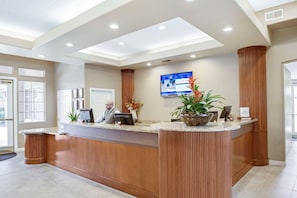 A reception desk with a digital display, a receptionist, and a potted plant. - Las Vegas | Couples Vegas Escape | Pool + Hot Tub (Las Vegas)